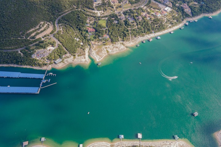 Aerial view of a lake with docks and nearby forested area.